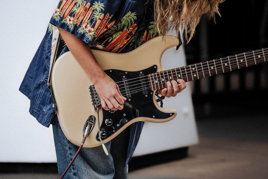 Ein Teenager in einem hawaiianischen Hemd und Baggy-Jeans spielt eine goldene E-Gitarre.