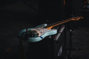Türkisfarbene E-Gitarre liegt auf einem Verstärker im dunklen Studio