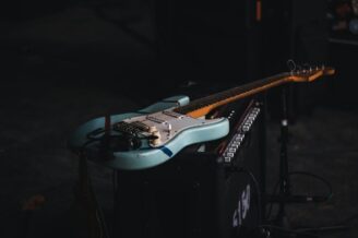Türkisfarbene E-Gitarre liegt auf einem Verstärker im dunklen Studio