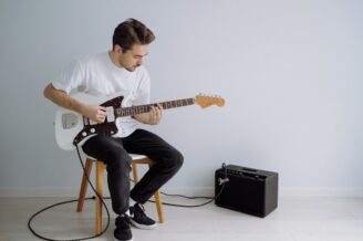 Gitarrist spielt E-Gitarre neben einem Verstärker im Proberaum